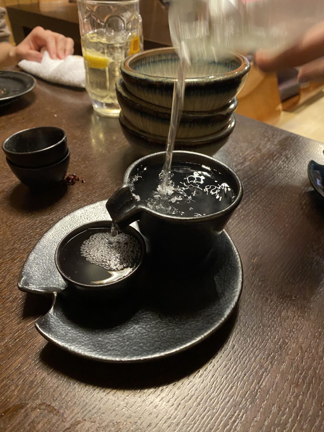 日本酒を溢れるくらい注いで貰っている写真