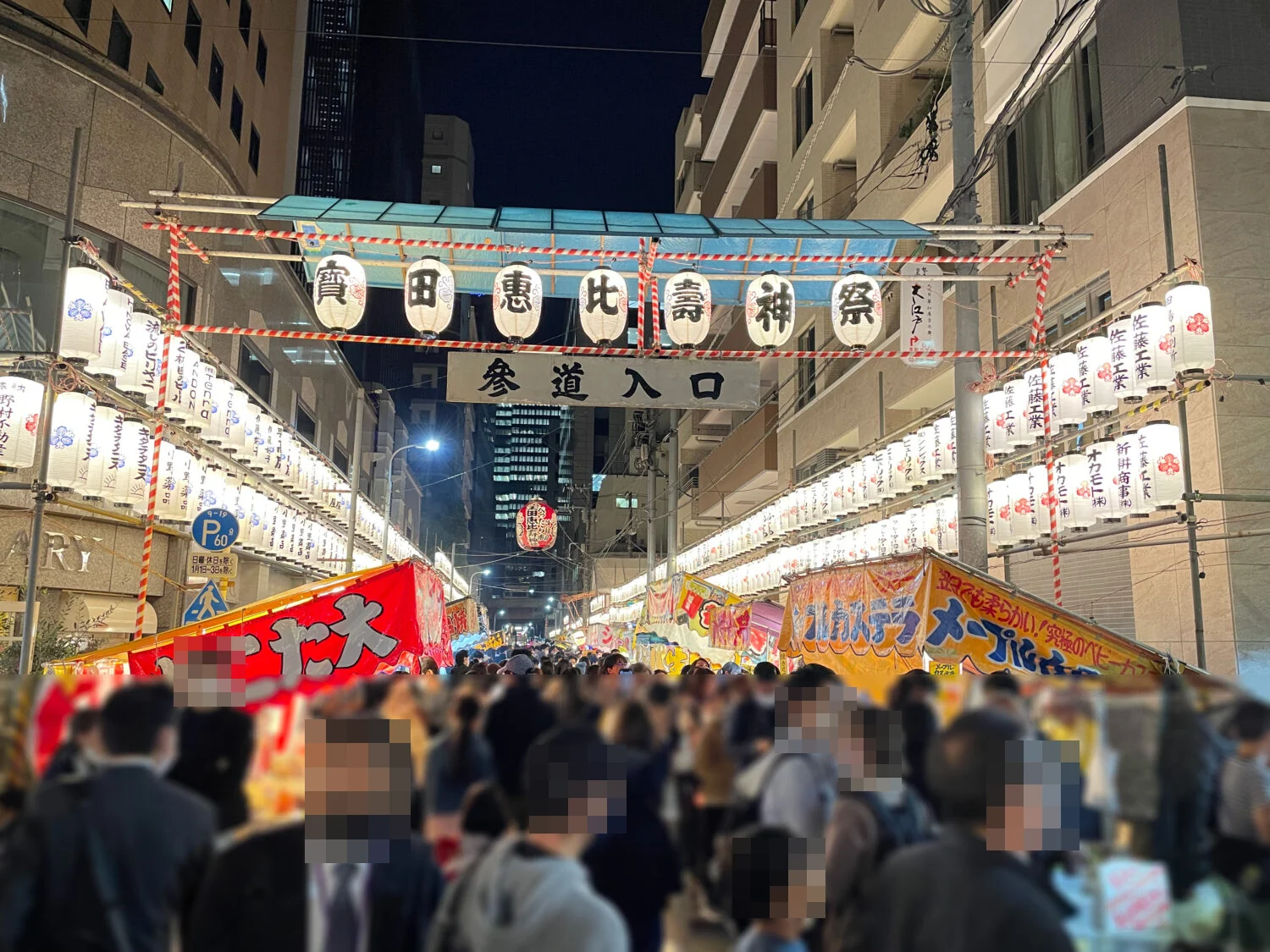 夜のべったら市で「寶田恵比壽神祭」と「参道入口」の提灯の門に続く人の波(2022年)