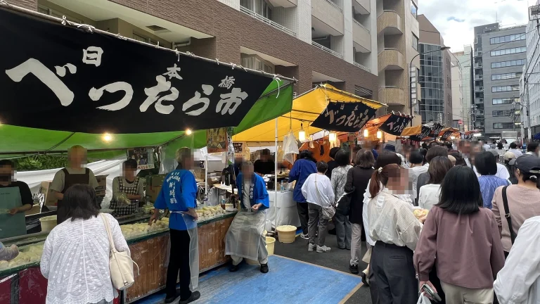べったら市の幕の下でべったら漬けを売る露店と人の流れ