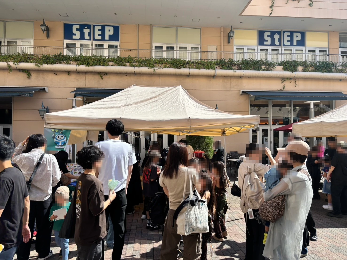 リテラんの旗を掲げたツカモトコーポレーションのブースのテントと来場者